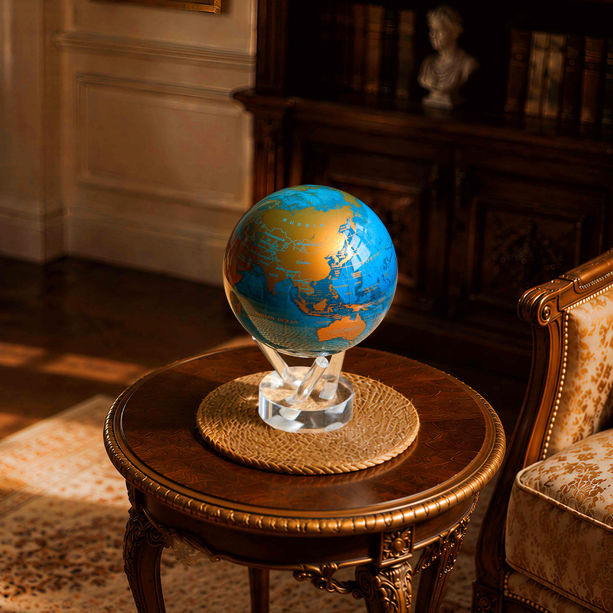 Cerulean Blue &amp; Gold MOVA Globe displayed atop a classic wooden side table in an elegant library interior.